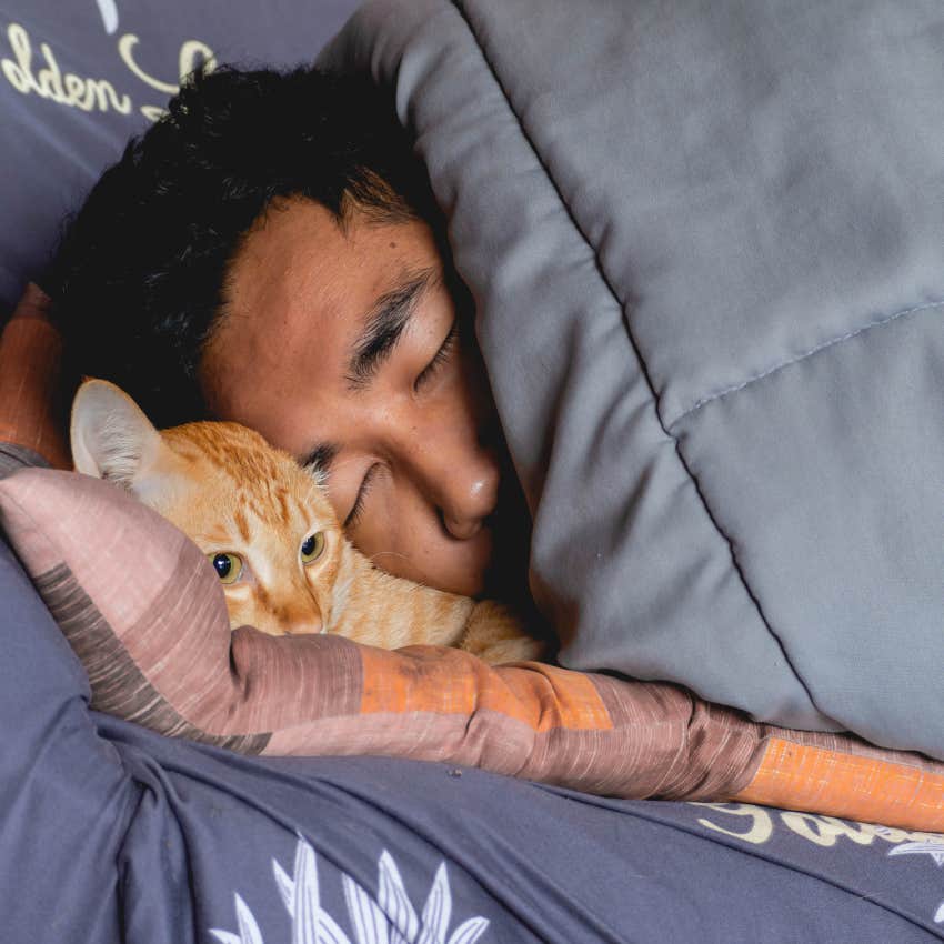 man snugging in bed with his cat who is his best friend