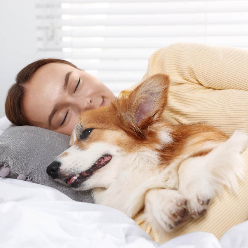 woman sleeping heavily in bed while spooning her dog