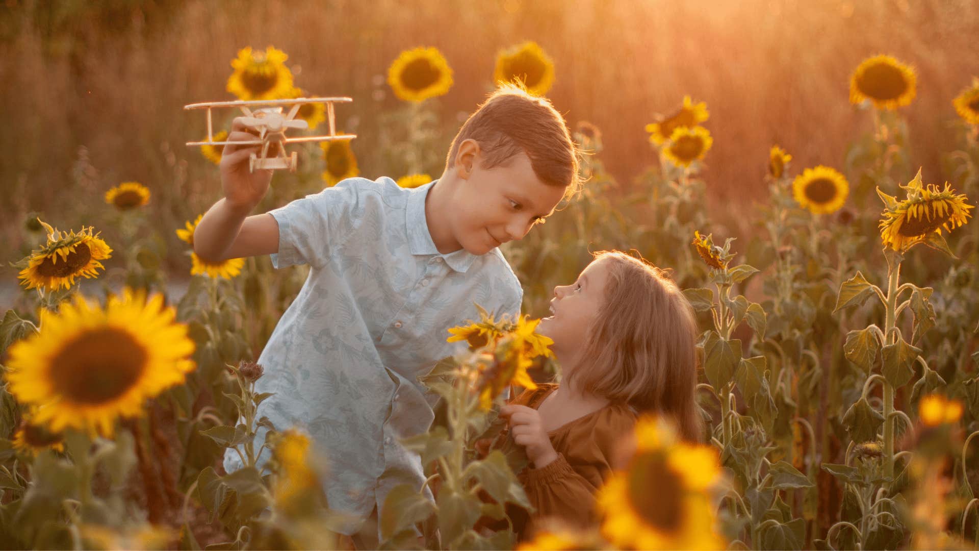 young siblings playing unsupervised outside in a sunflower field