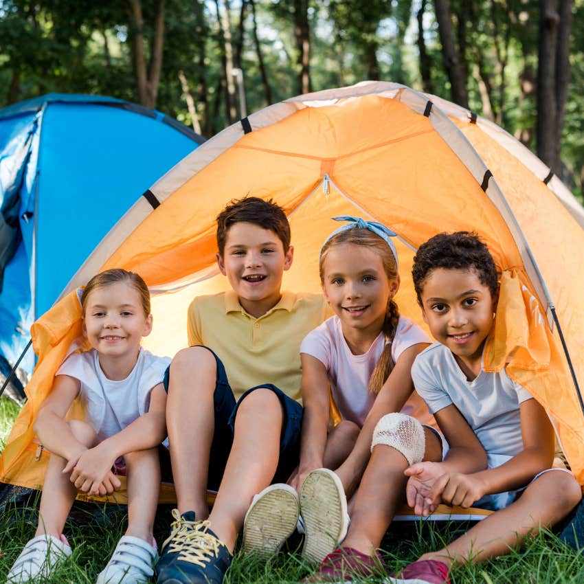 kids sitting outside of a tent while camping
