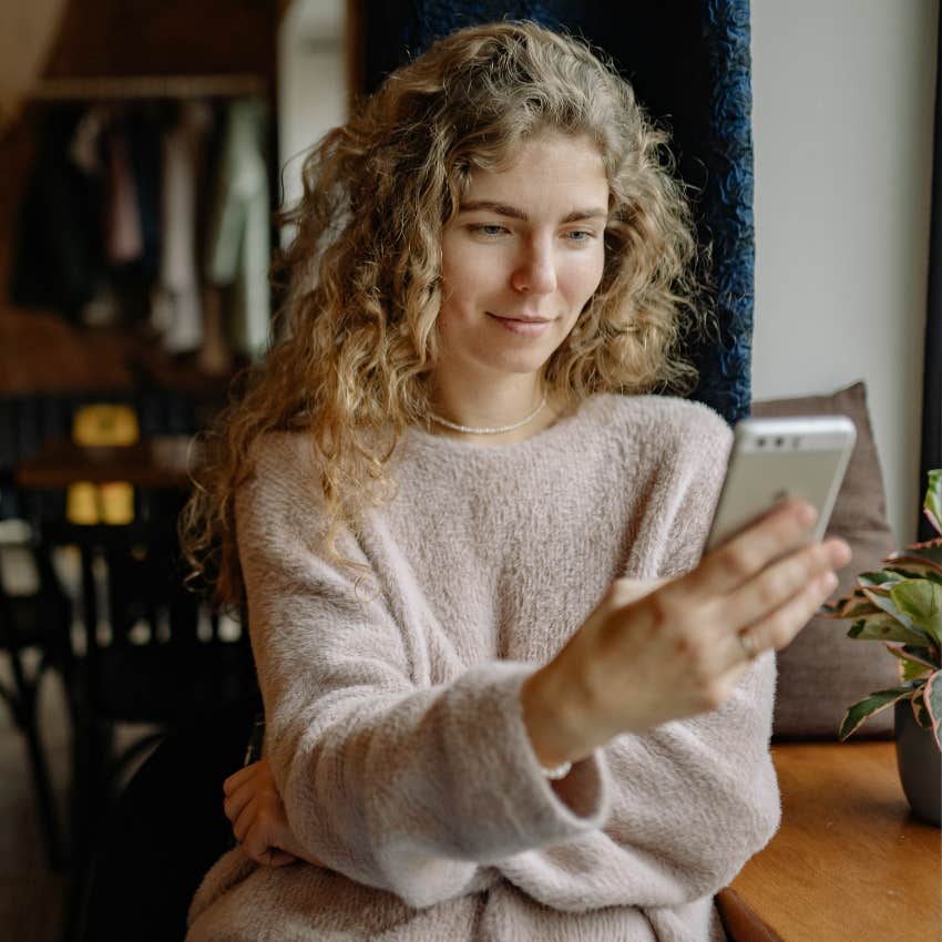 woman going through her partner's phone smiling