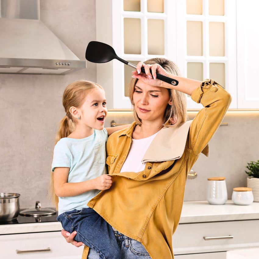 exhausted mom holding daughter while cooking saying I'll eat later
