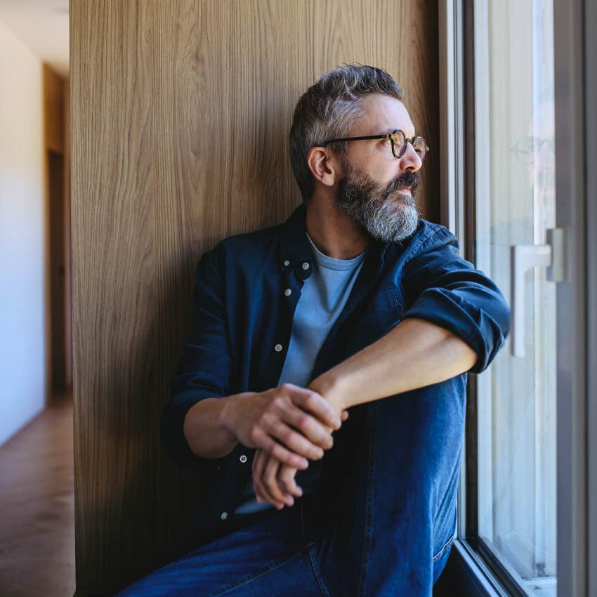 Man who refuses to dwell on the past looking out a window at home.
