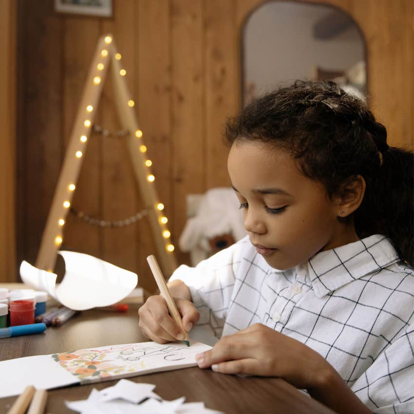 Child drawing and writing creative ideas in a notebook at home without worrying about perfection