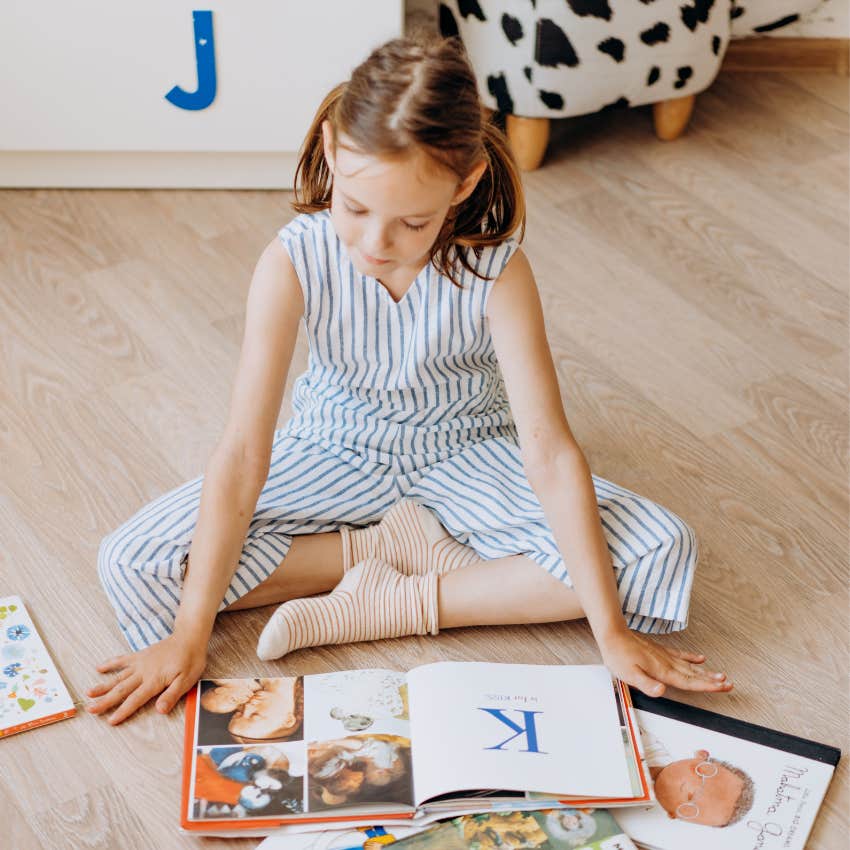 Child from the 1980s or 1990s sitting on the floor reading a book for fun