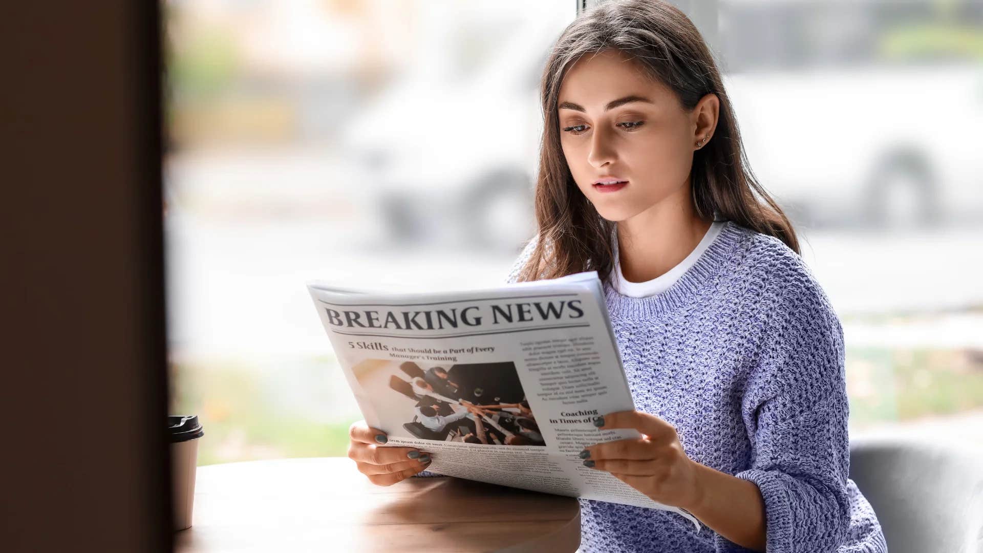 gen Z woman reading a physical newspaper