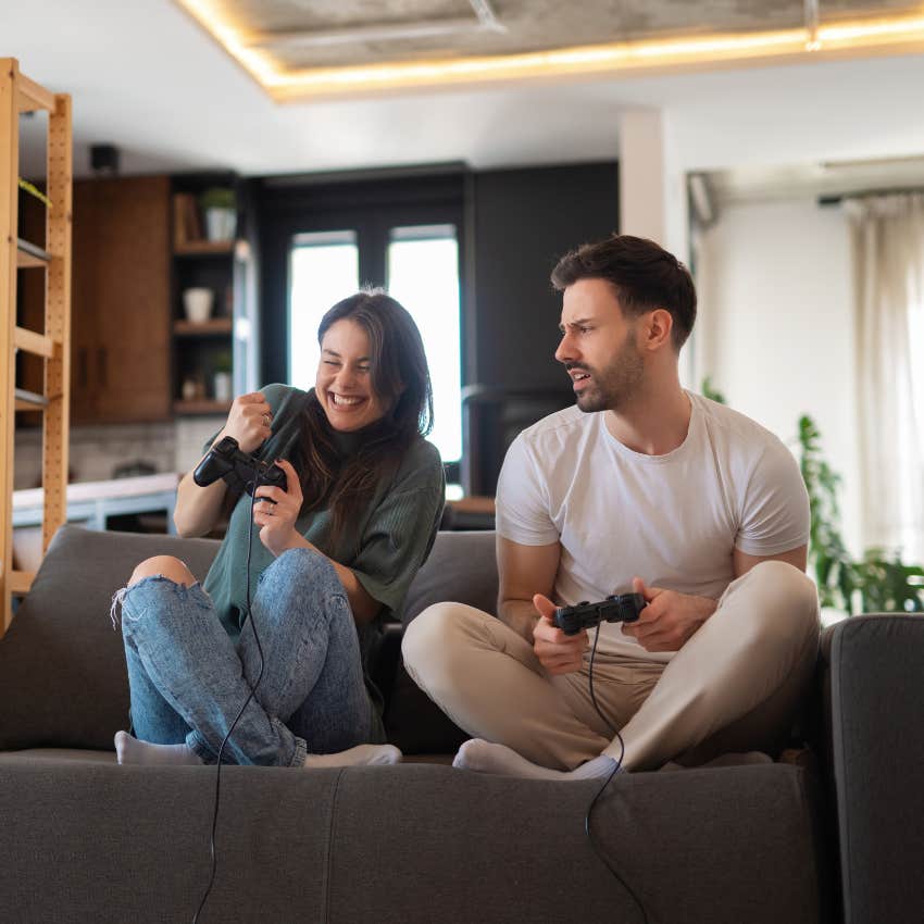 happy couple playing video games on living room couch