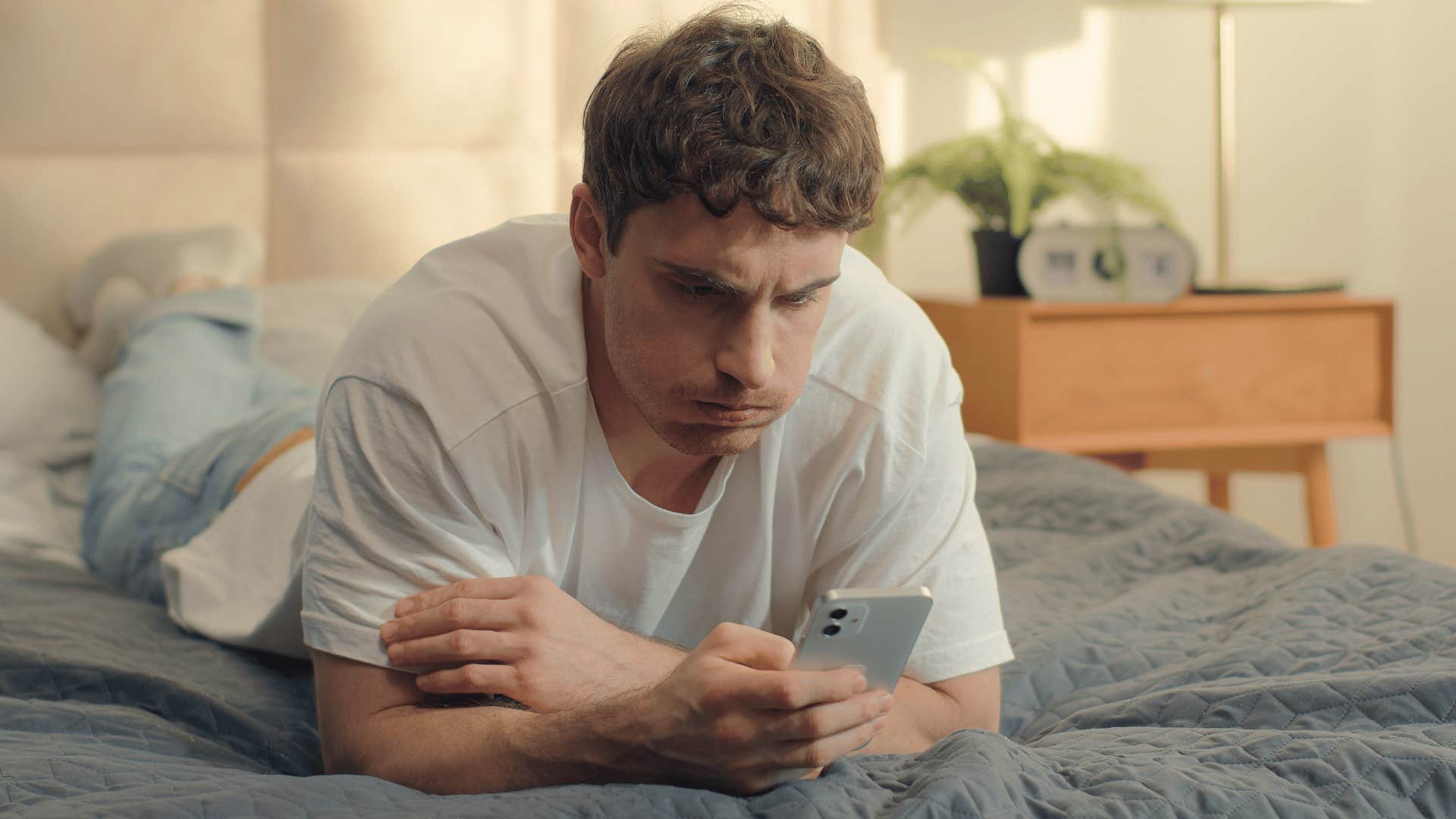 man on bed upset as he texts good for you i guess
