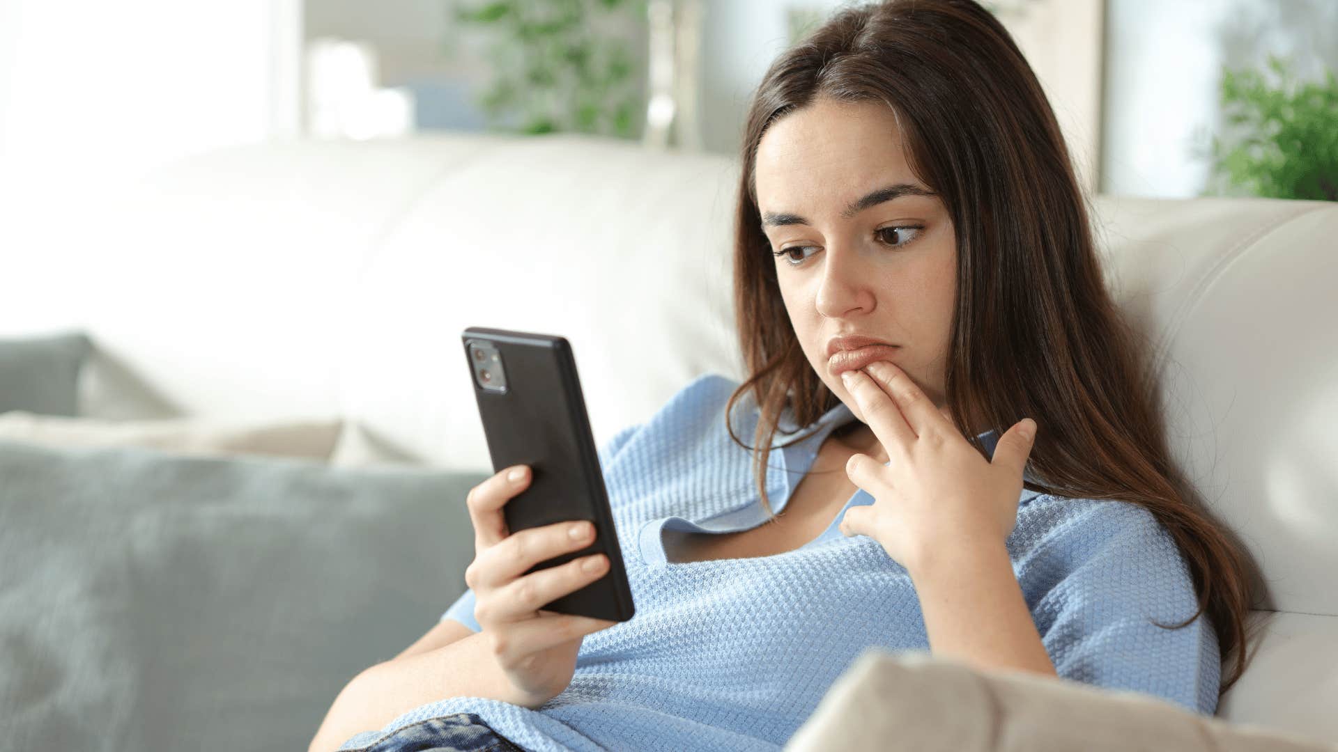 woman in blue shirt on phone looking unimpressed as she thinks wow you're so lucky things always work out for you