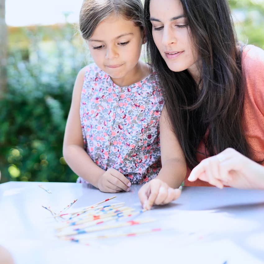 mom playing pick up sticks with her child