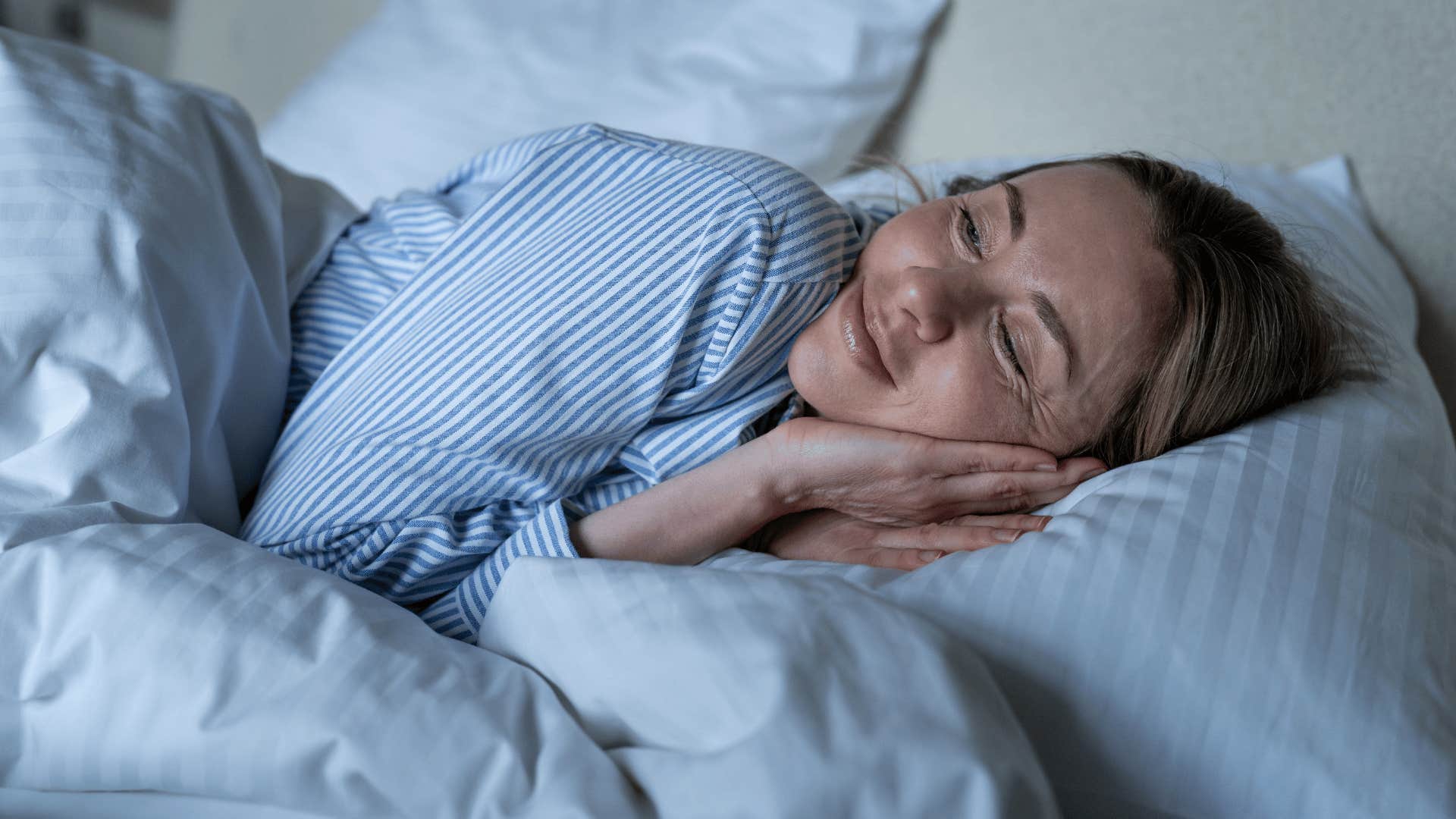 gen X woman laying happy in bed going to sleep early