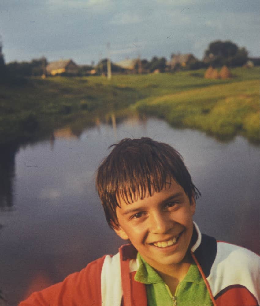 Gen X boy posing by a river in the 1980s with no parent watching over him 