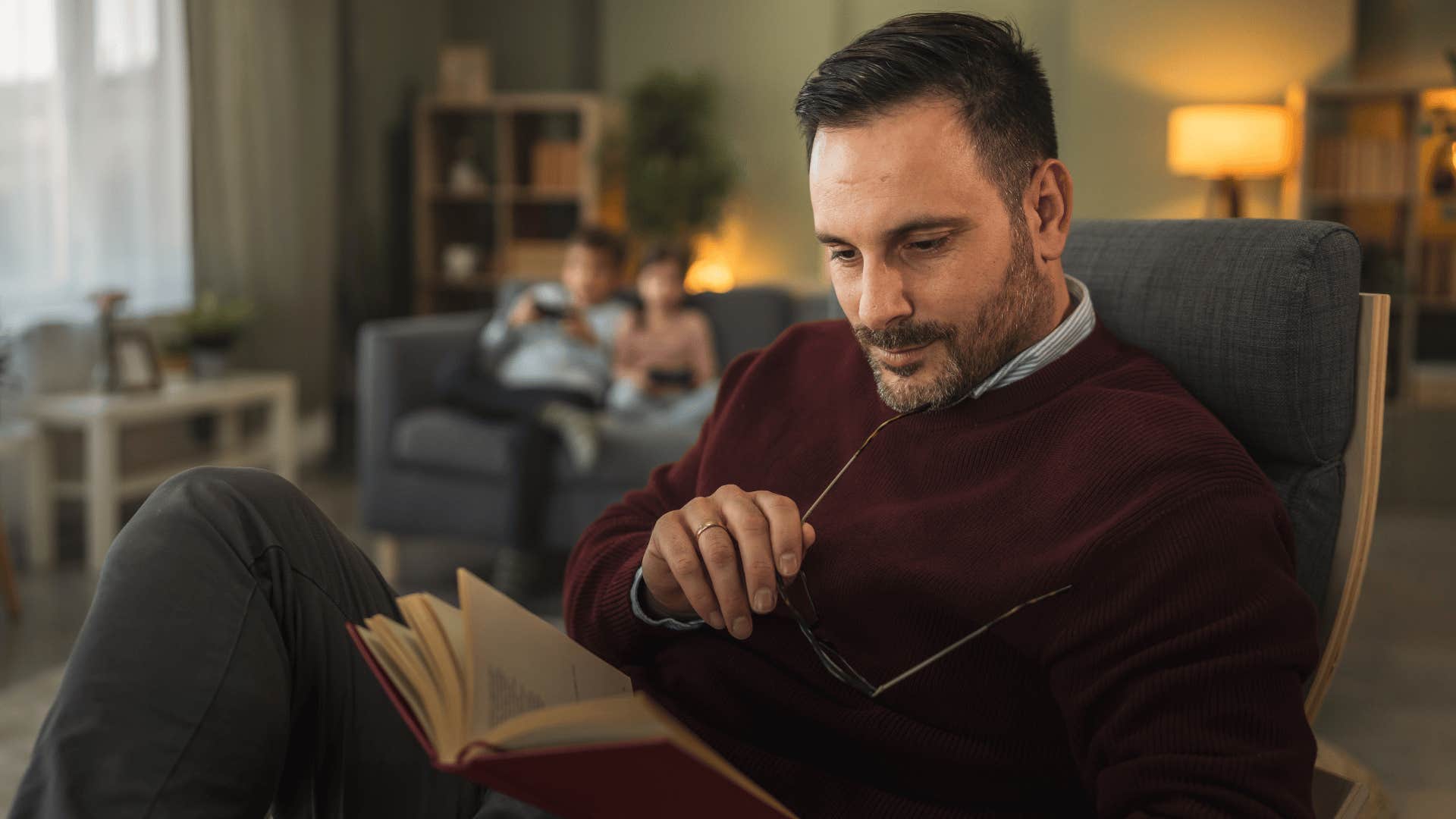 man who was a gifted kid becoming completely absorbed in a new interest as he reads book on chair