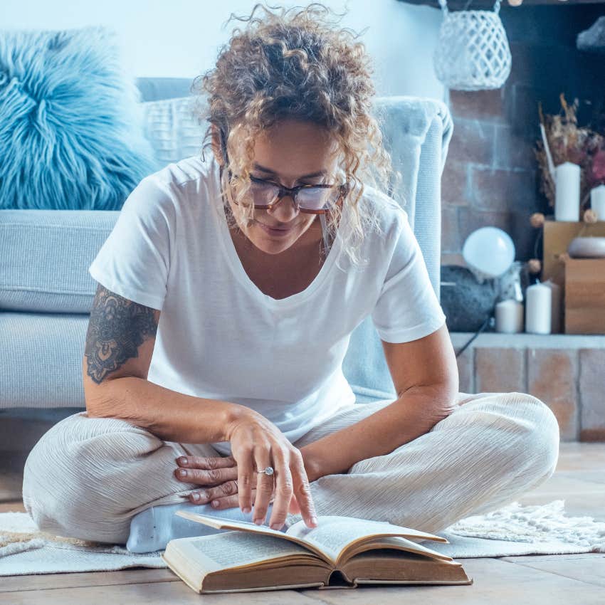creative woman sitting on the floor reading a book for inspiration