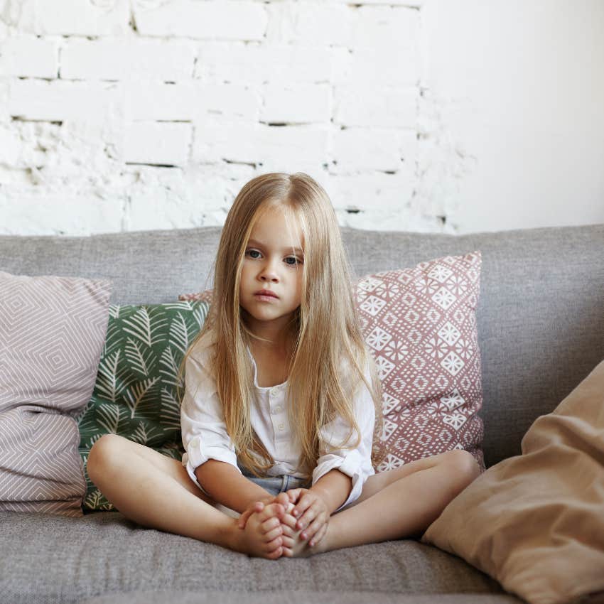 little girl raised by mentally emotionally distant parents sitting on couch talking bad about herself