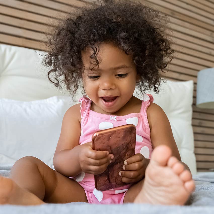 eighteen month old girl playing on parent's phone