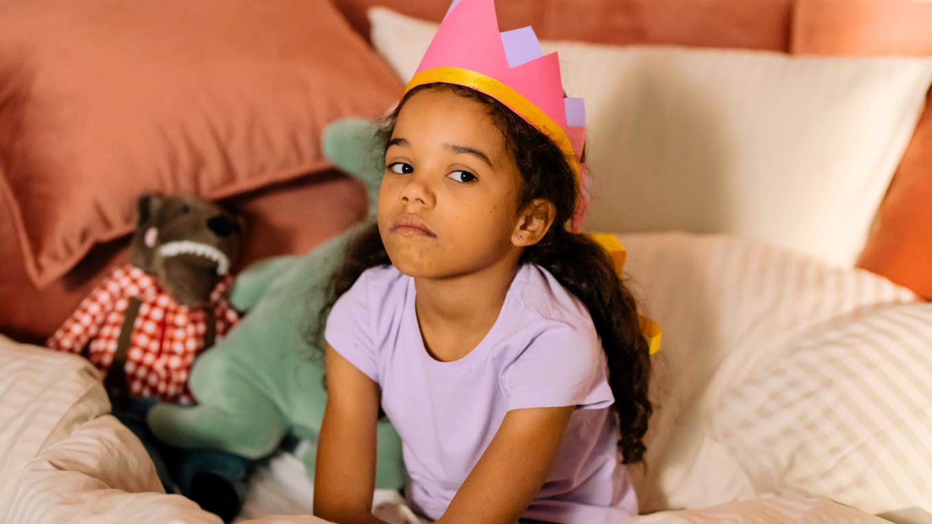 undisciplined little girl sitting in bed with a crown not listening