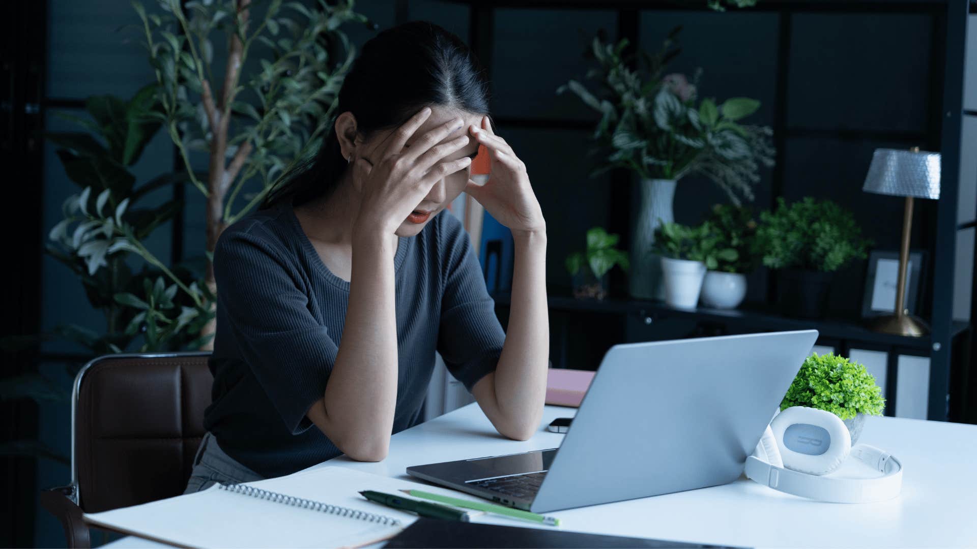 woman clutching head frustrated at work as she says i don't have the energy for this