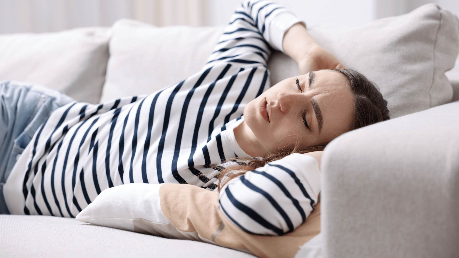 woman in stripped shirt laying on couch as she thinks i just need some alone time