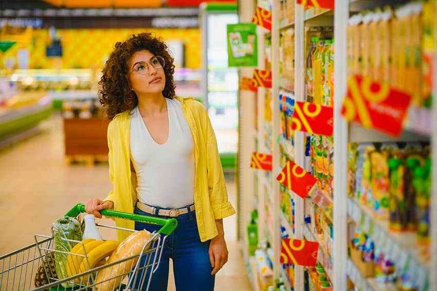 younger woman splurging on groceries because other luxuries are out of reach