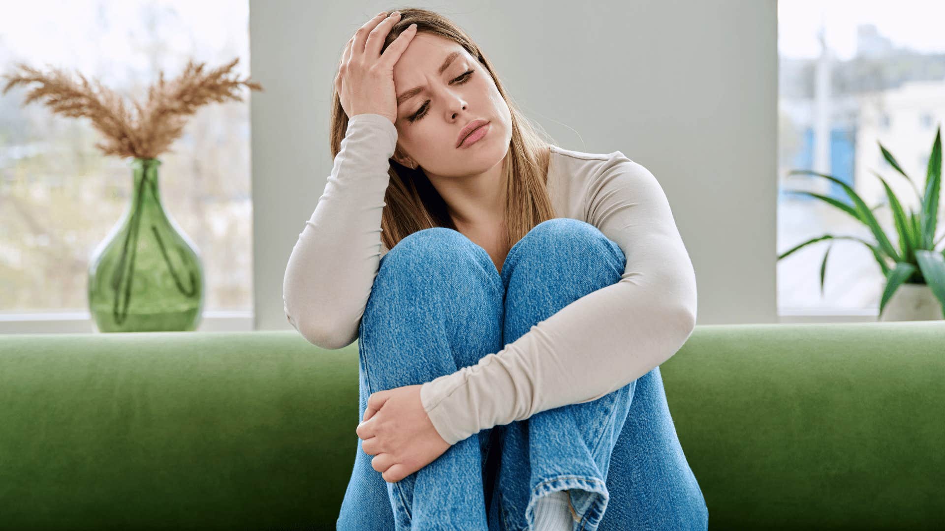 woman in white shirt sitting on couch stressed as she thinks i don't want to be selfish