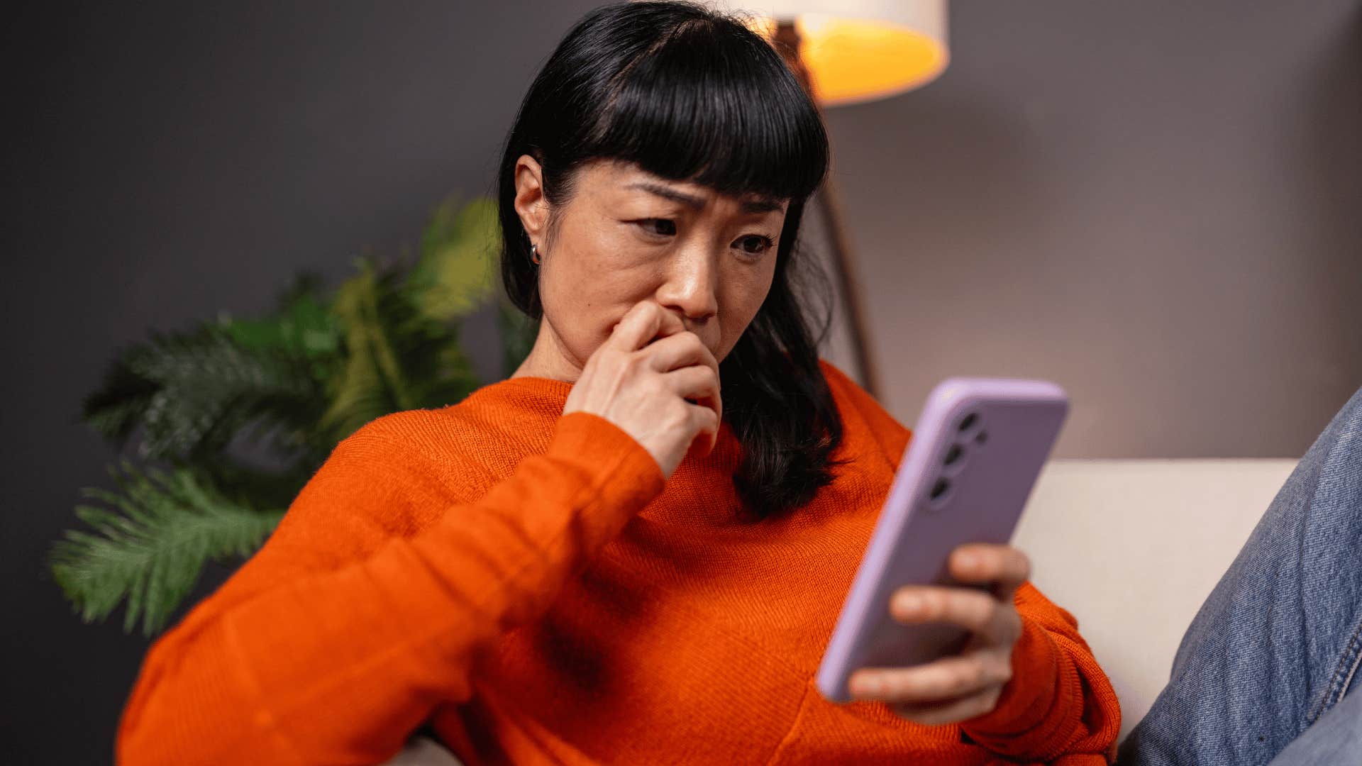 woman in orange shirt looking at phone as she thinks i don't want to make things awkward