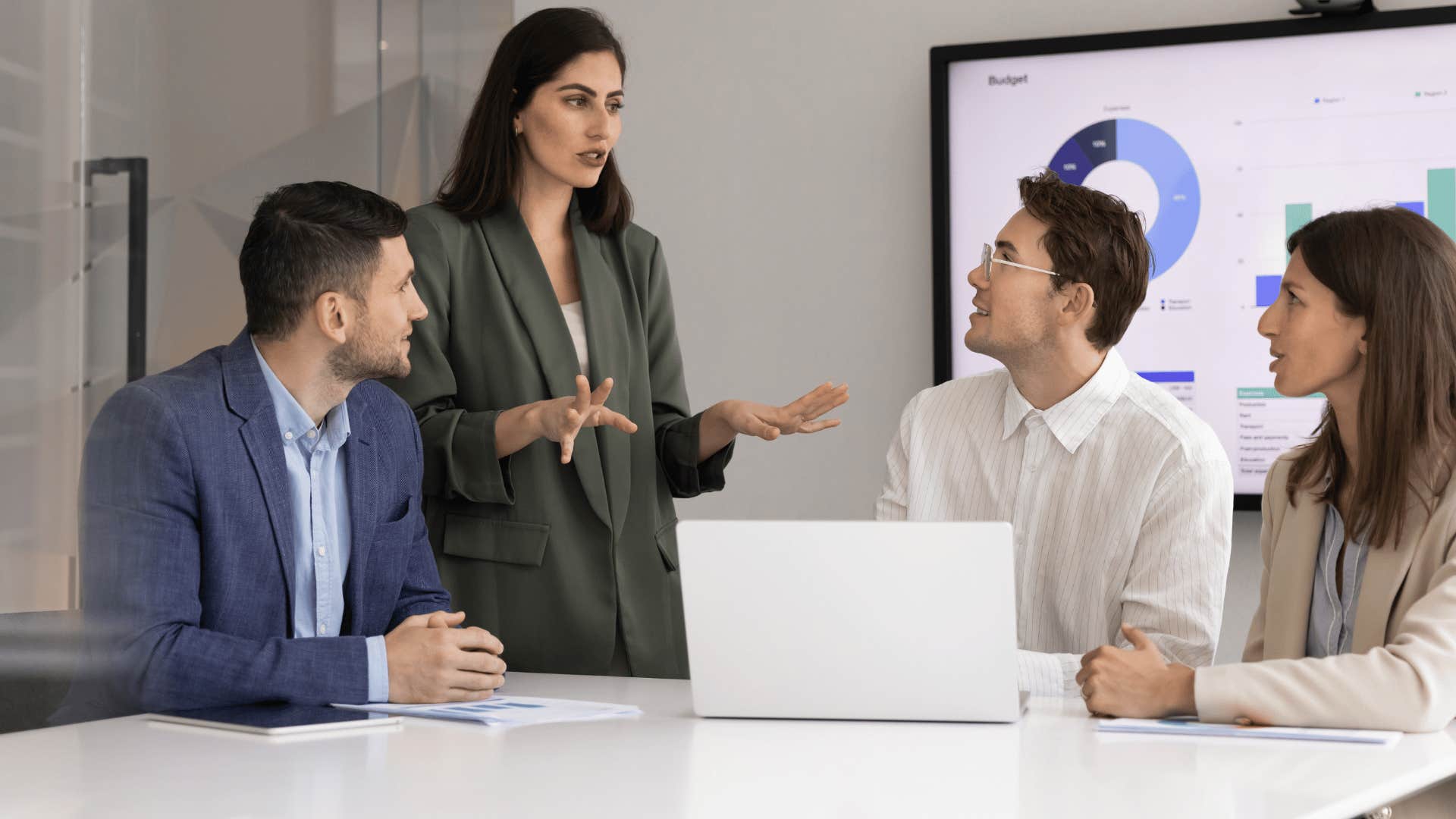 woman in green telling coworkers at meeting it's okay i'll just do it