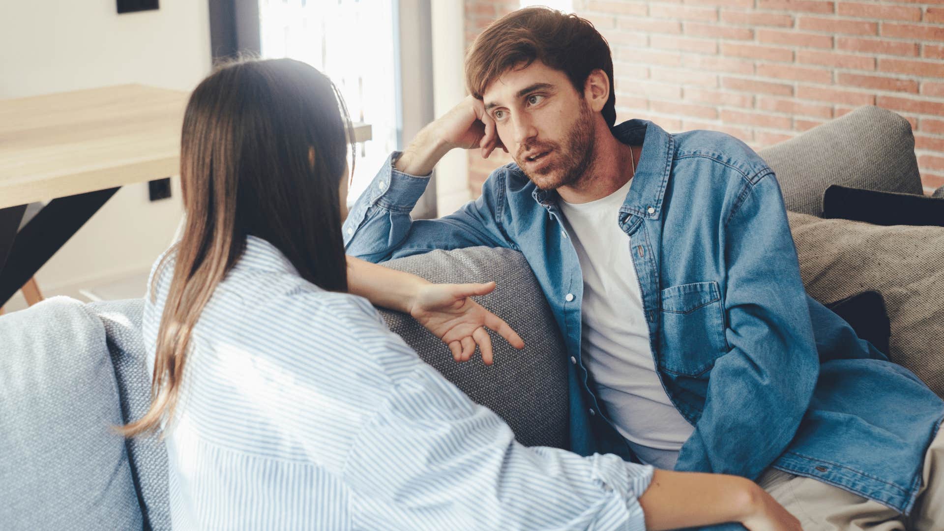 man looking at woman talking on the couch as he says i see where you're coming from