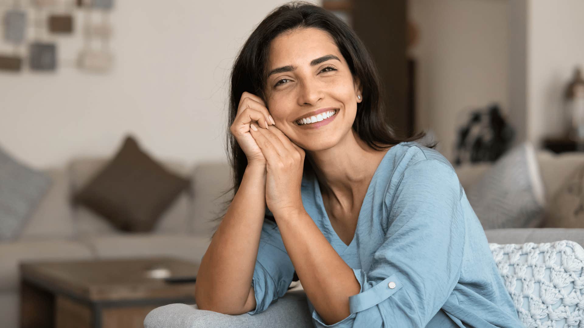 woman in blue shirt smiling brightly at camera as she thinks it's no biggie