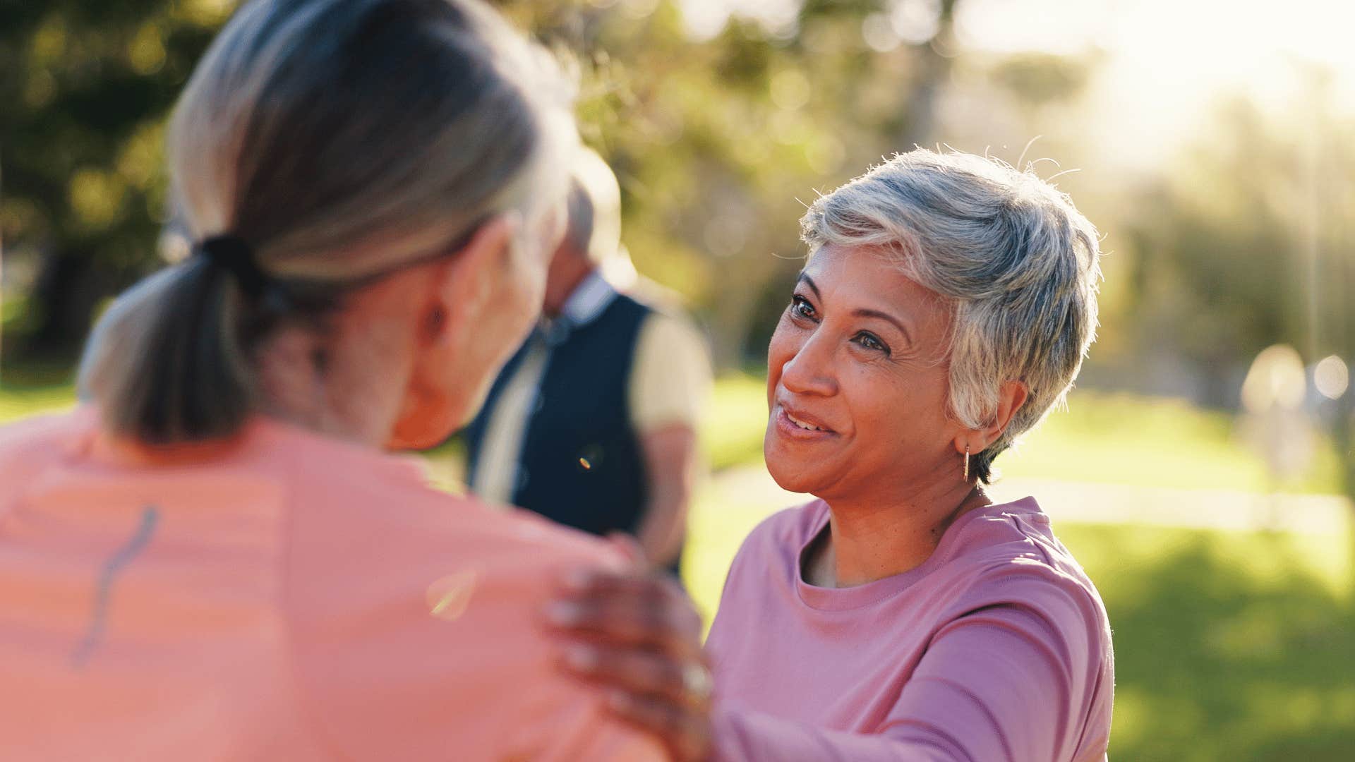 older woman in pink shirt telling friend no worries