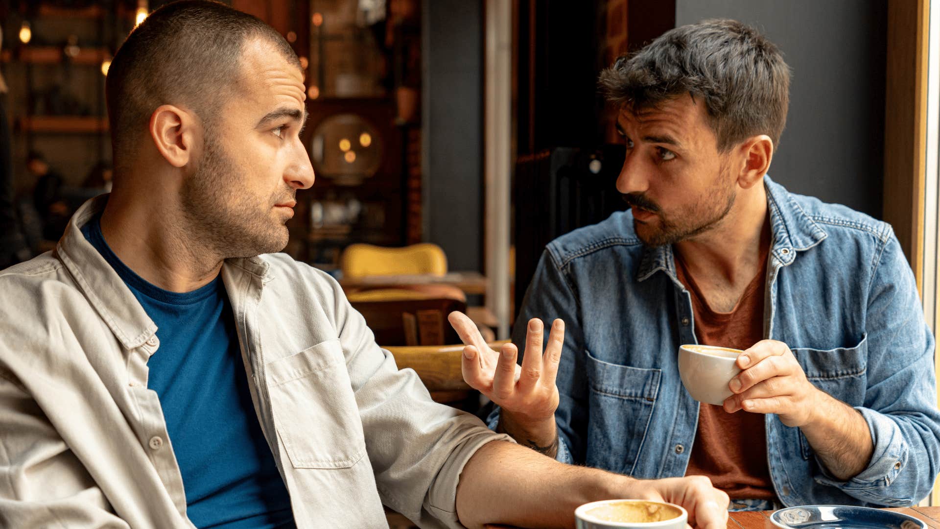man in jean jacket telling friend at cafe we can talk about it later