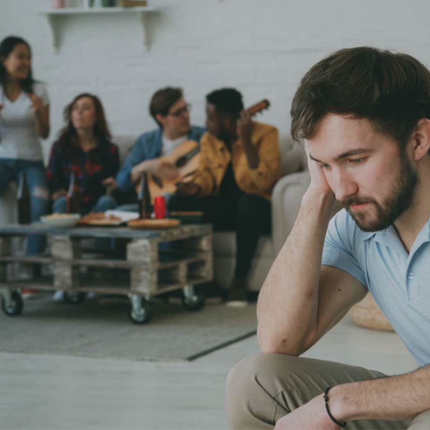 lonely man sitting apart from friends feeling rejected