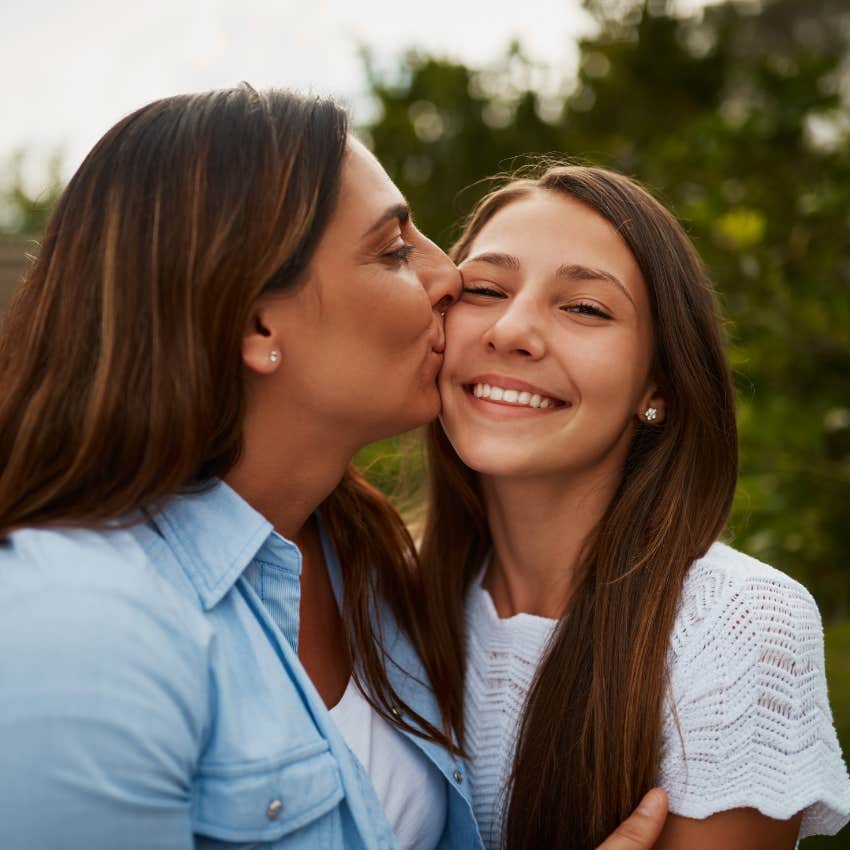 mom kissing teen daughter showing her how proud she is