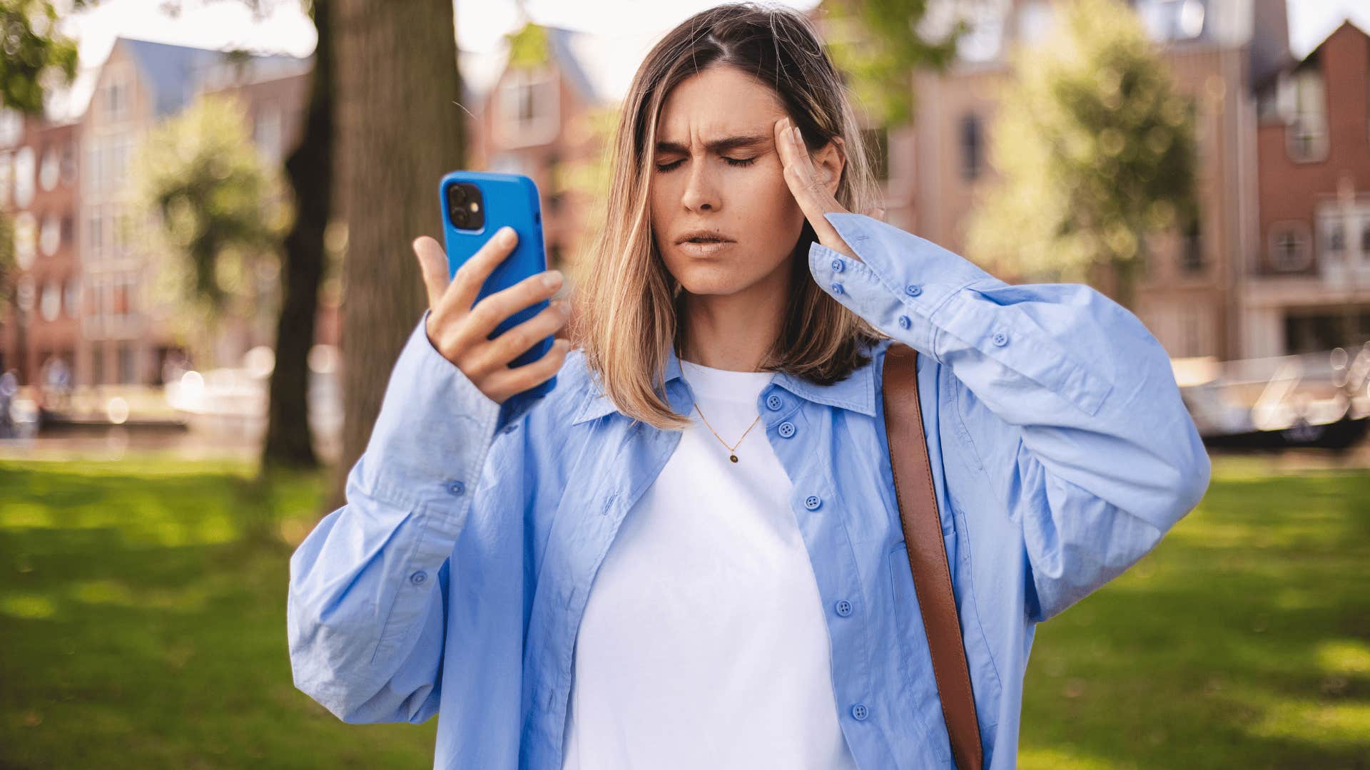 woman in blue jacket looking perplexed as she thinks that's just common sense while staring at her phone