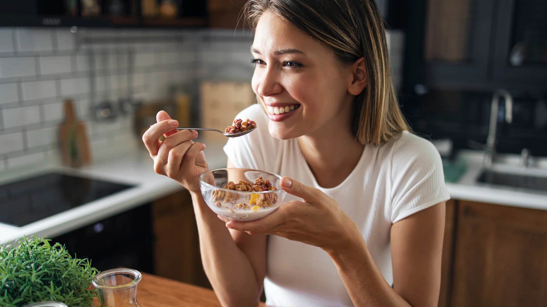 happy young woman eating a healthy breakfast at home