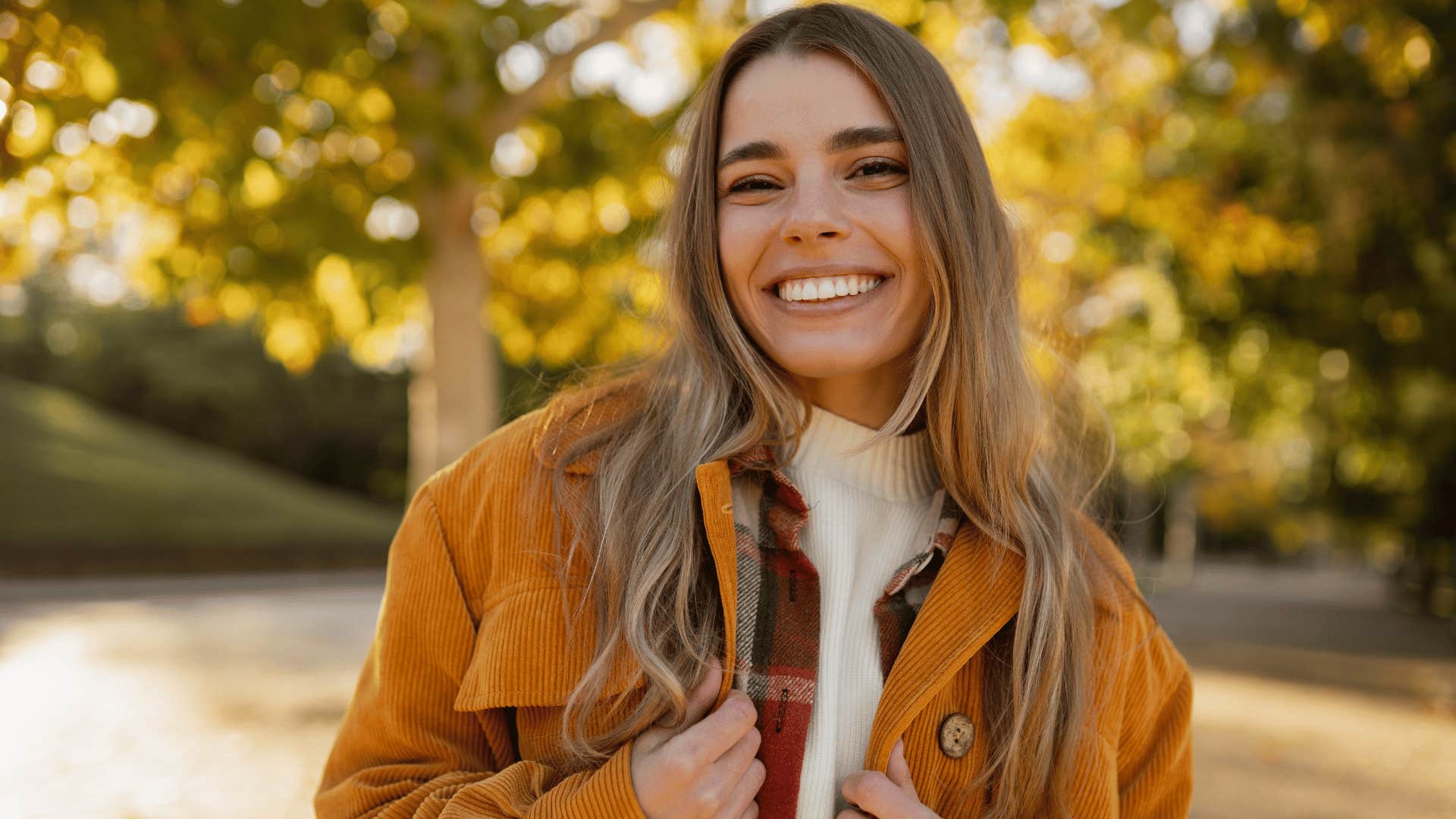 woman in burnt orange jacket smiling brightly as she says you only live once