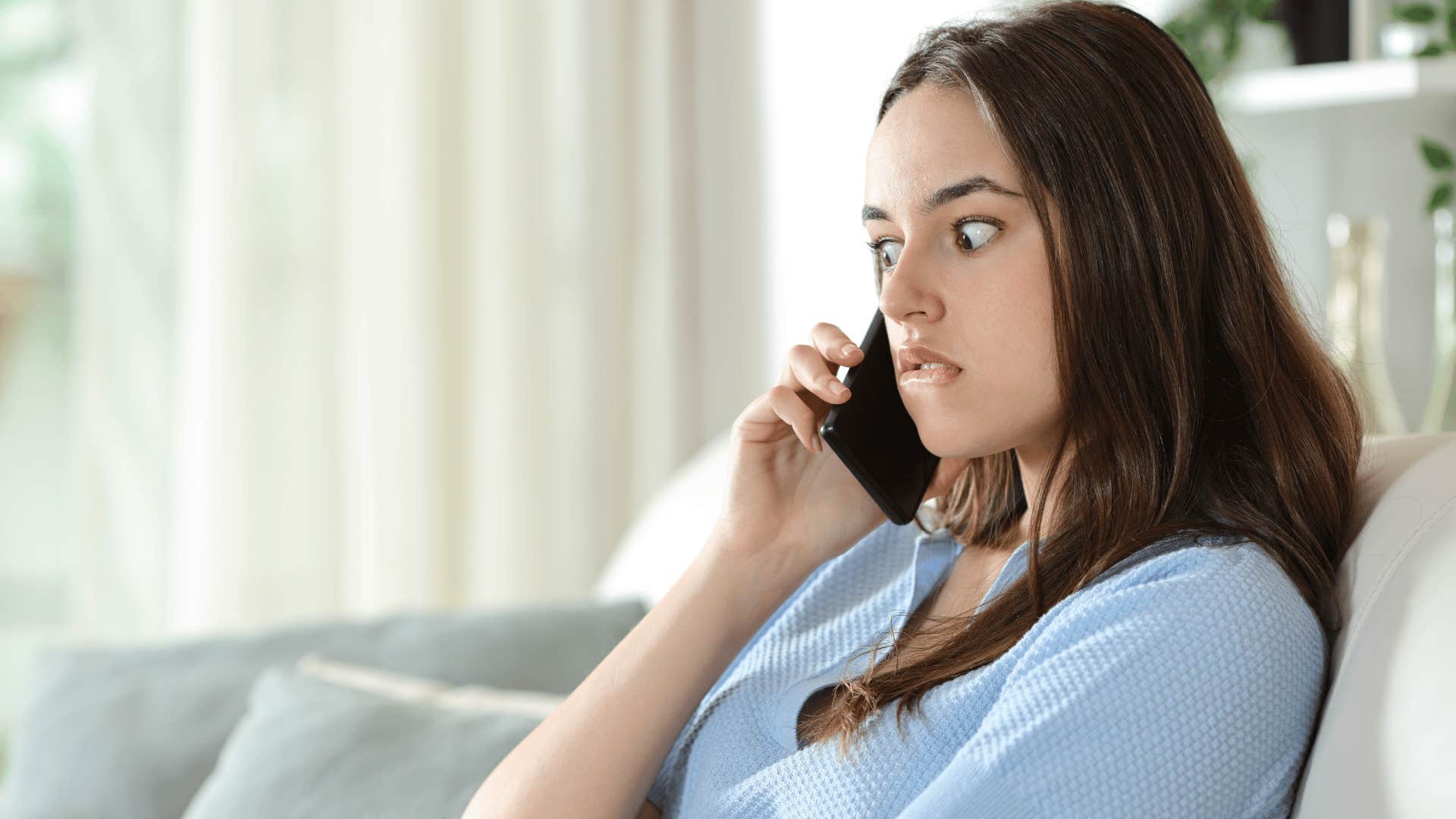 woman in blue shirt cringing on phone as she says anyway