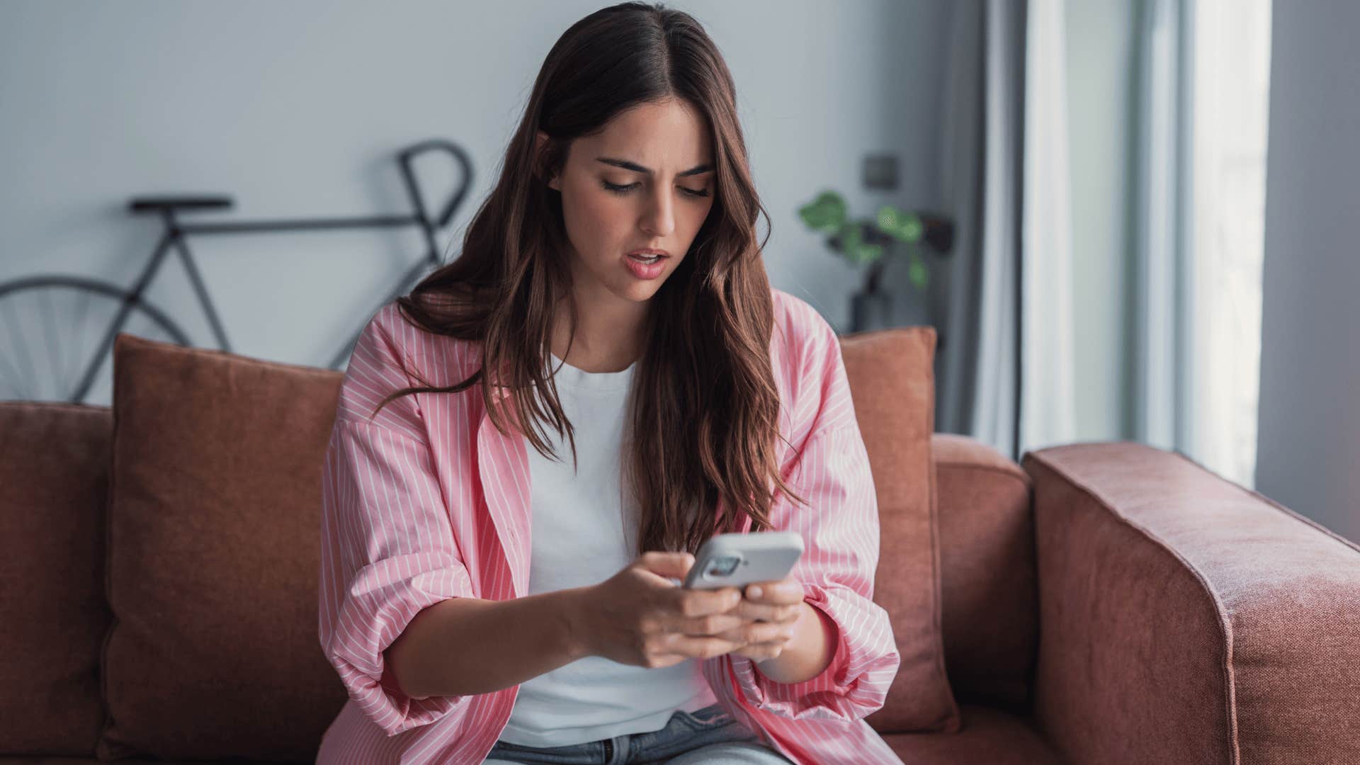 woman in pink jacket looking at phone as she thinks did i make things weird