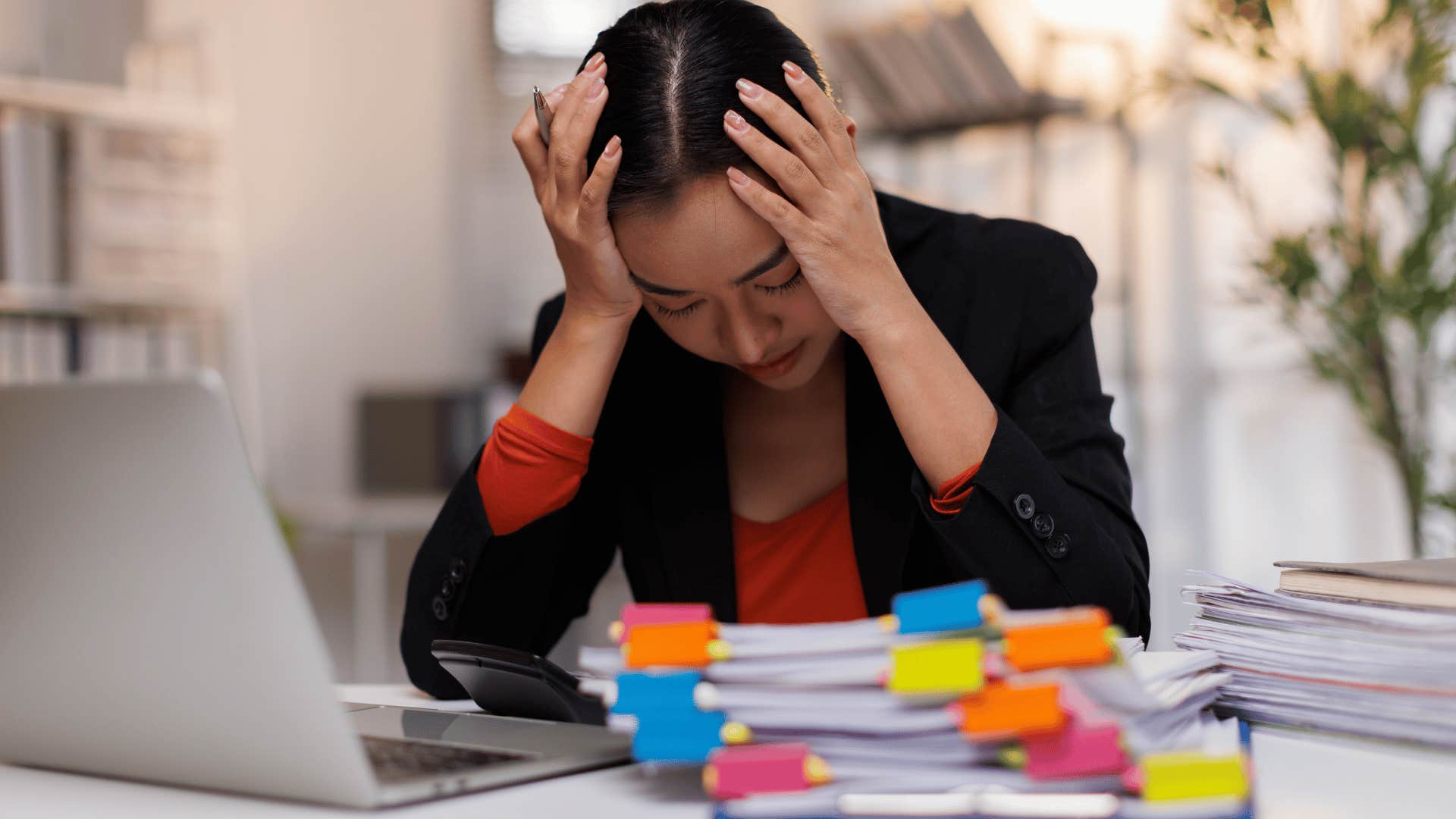 woman clutching head frustrated at work as she thinks i'm at my limit