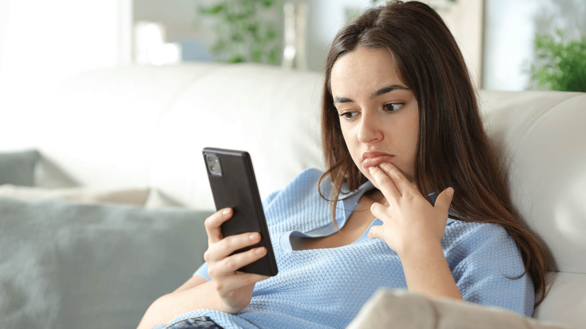 woman in blue shirt staring at phone thinking i'm just over it