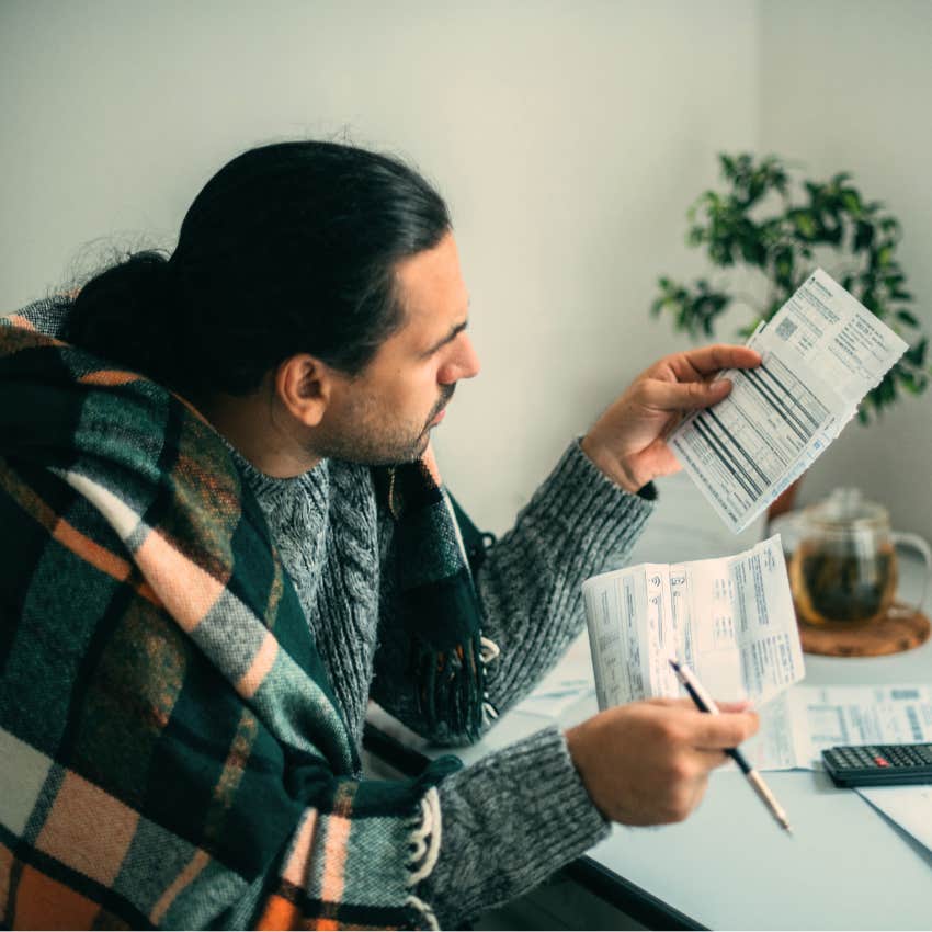 Man with paper trails and analog habits at home doing bills.