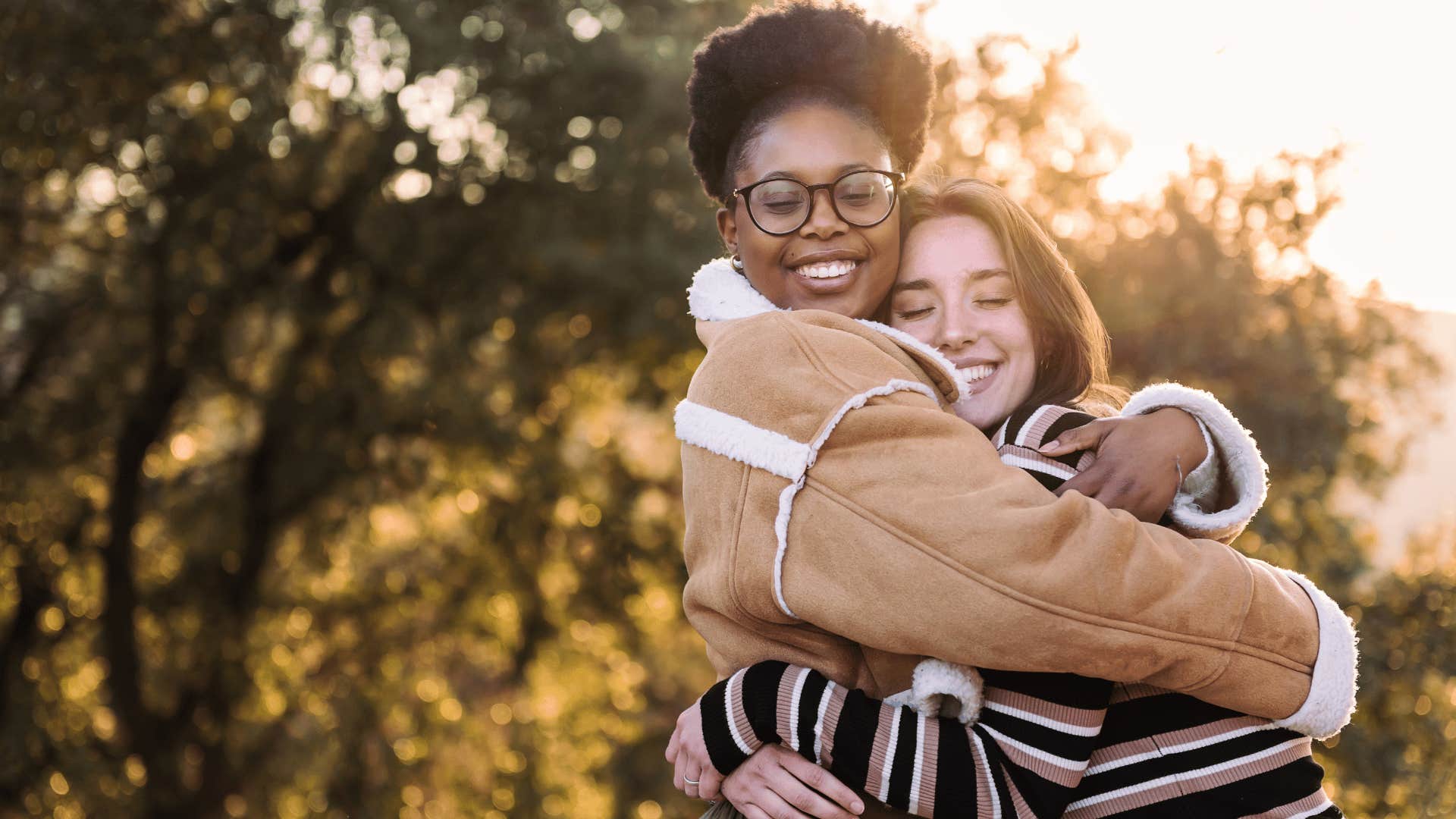 woman in brown coat hugging friend as she feels a sense of belonging