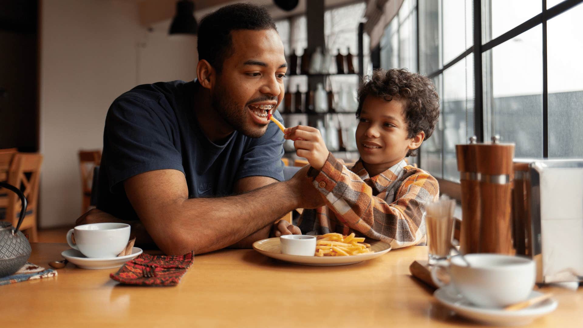 little boy feeding father as it's their family ritual to go out to breakfast
