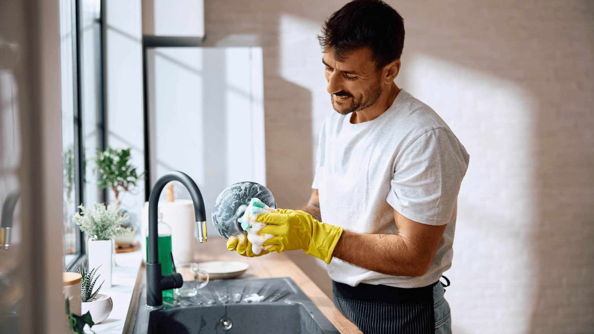 man in white shirt washing dishes in his clutter free space