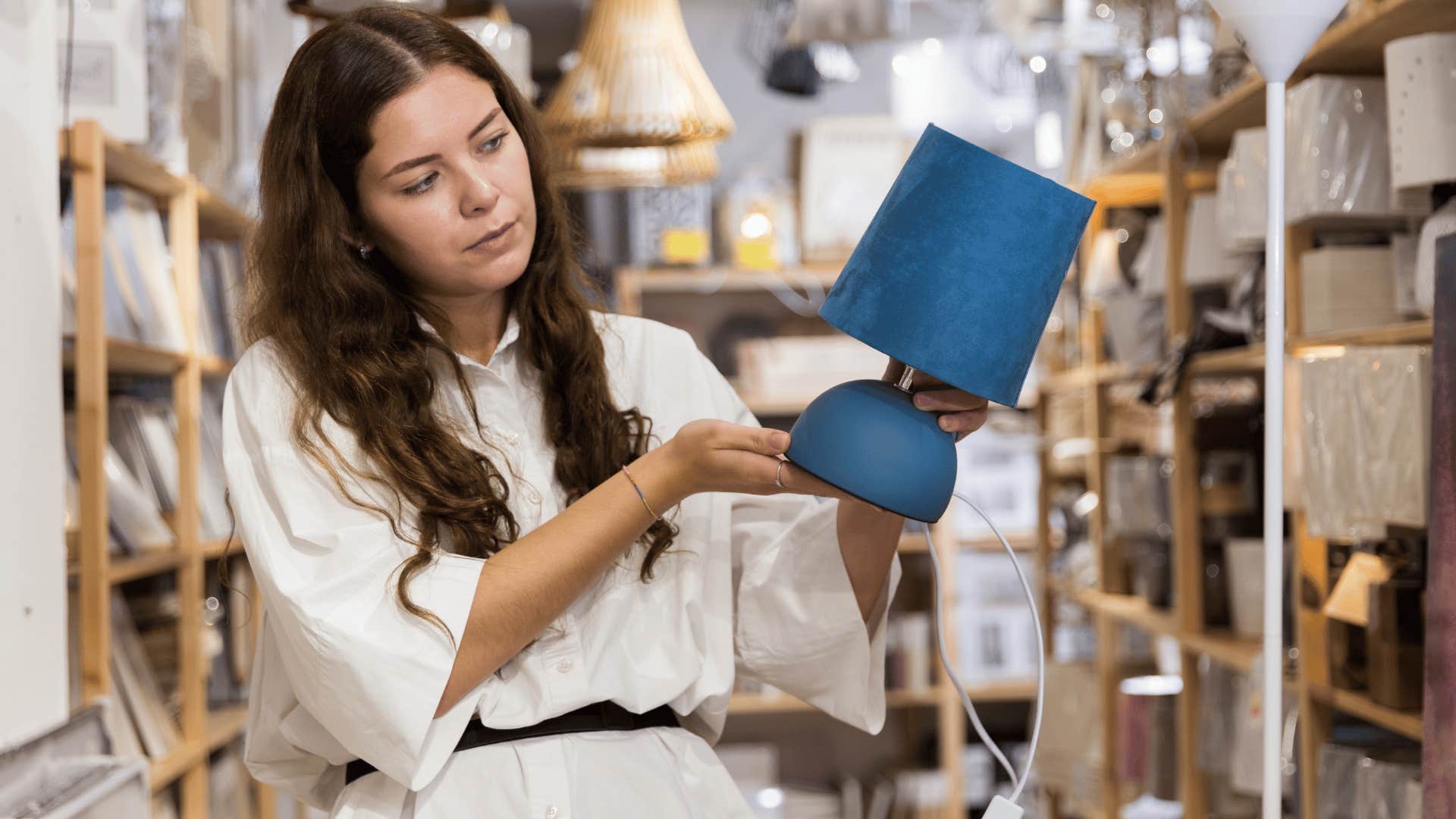 woman picking up blue lamp as it has soft lighting