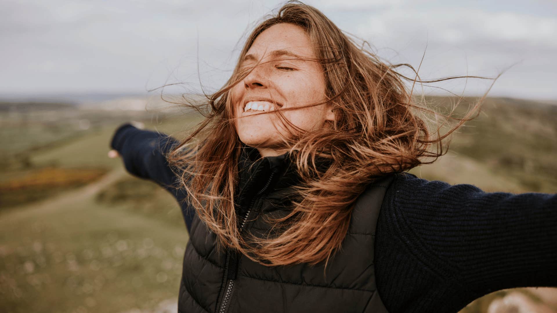 woman smiling brightly outside as she says good vibes only