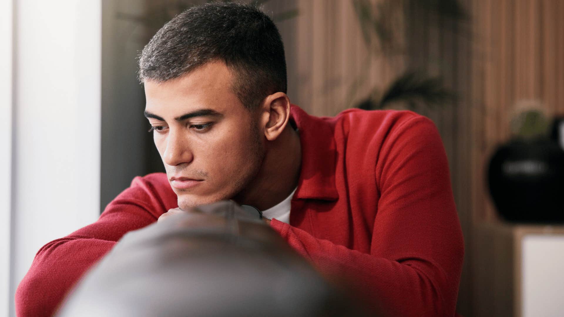 man in red shirt thinking you can't say anything anymore as he looks upset on couch