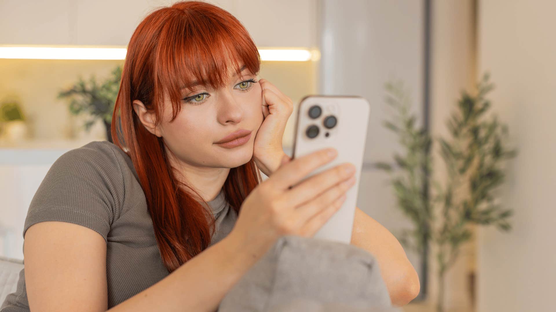 woman in gray shirt wasting time on trivial things as she scrolls on the phone