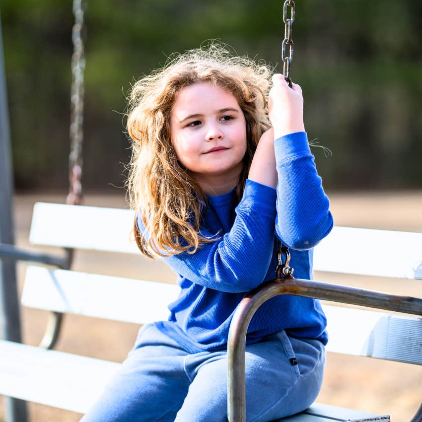 young girl entertaining herself on a park swing