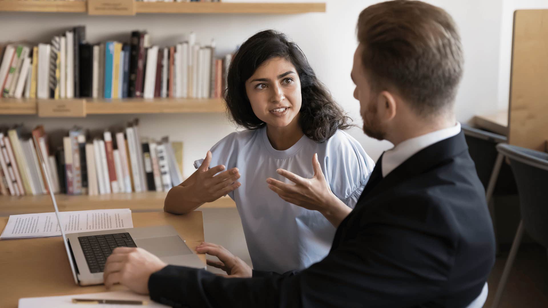woman in white shirt telling male coworker i don't know what do you think as they discuss